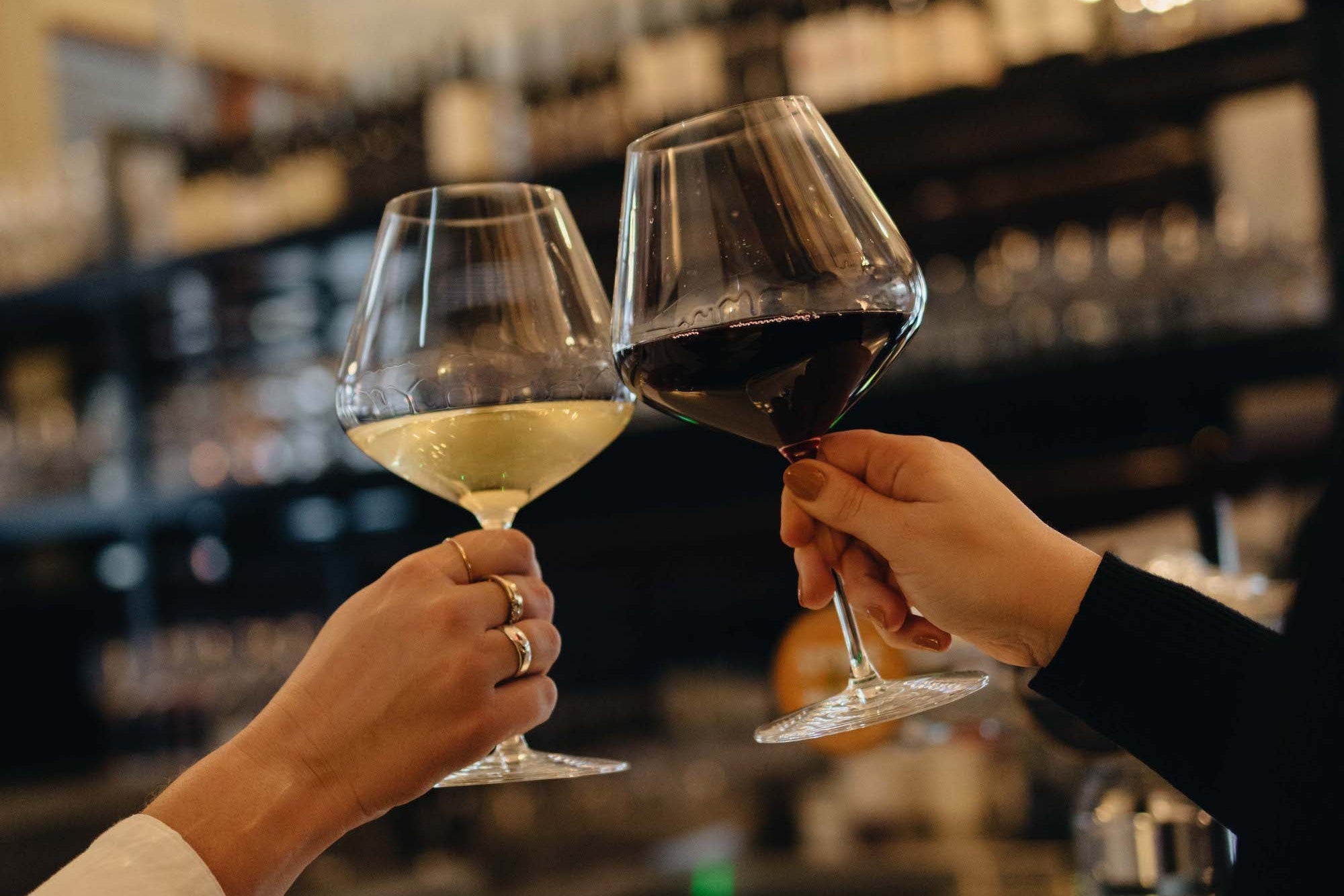 Two people clinking wine glasses in a bar setting