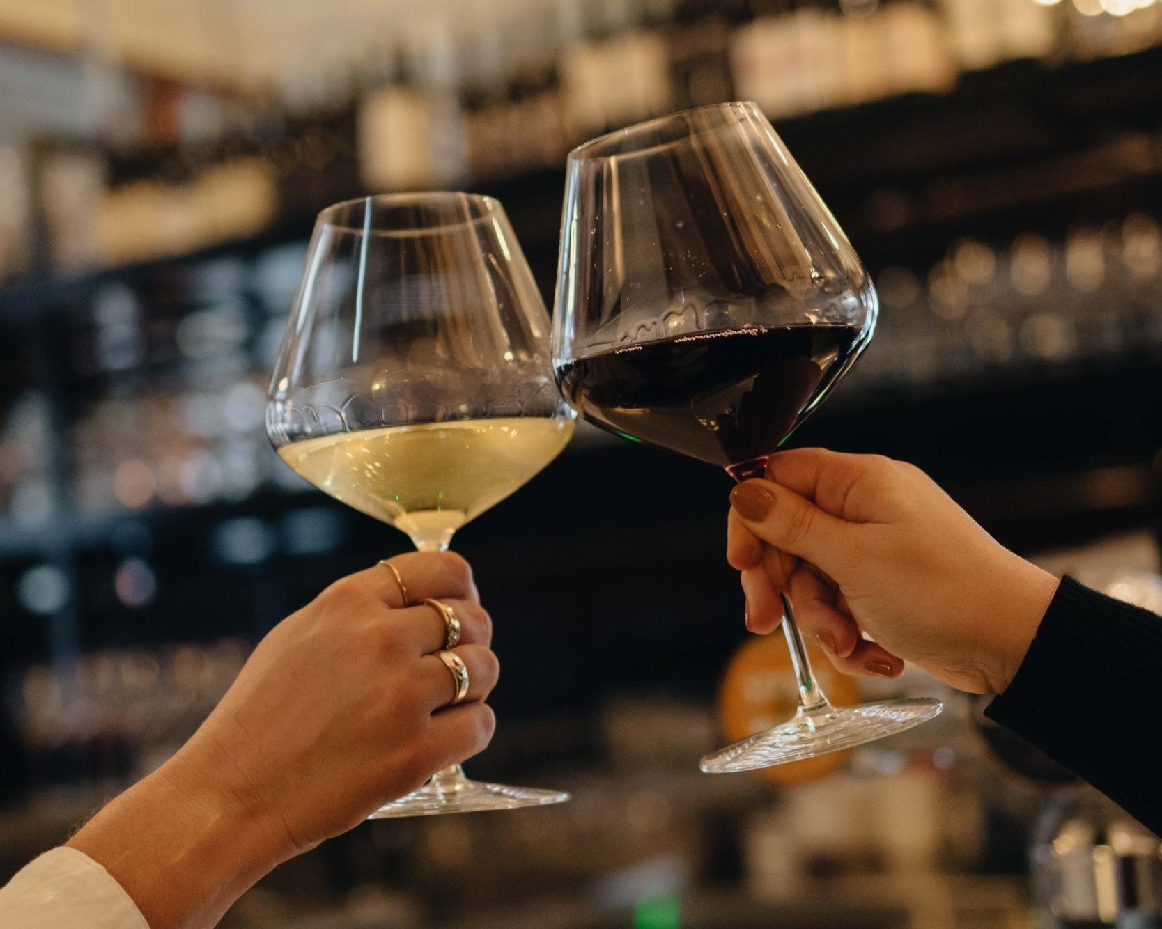 Two people clinking wine glasses in a bar setting