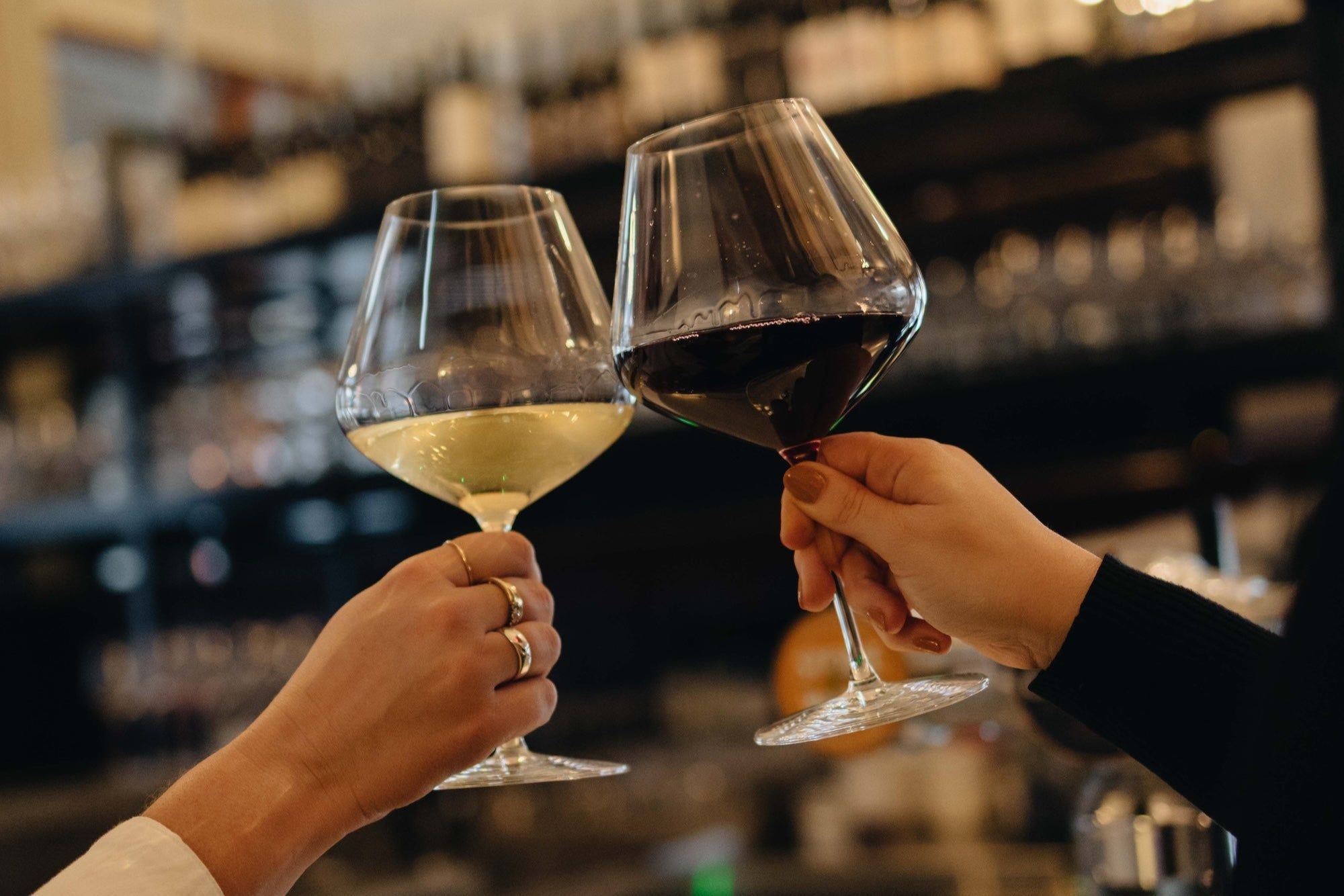 Two people clinking wine glasses in a bar setting