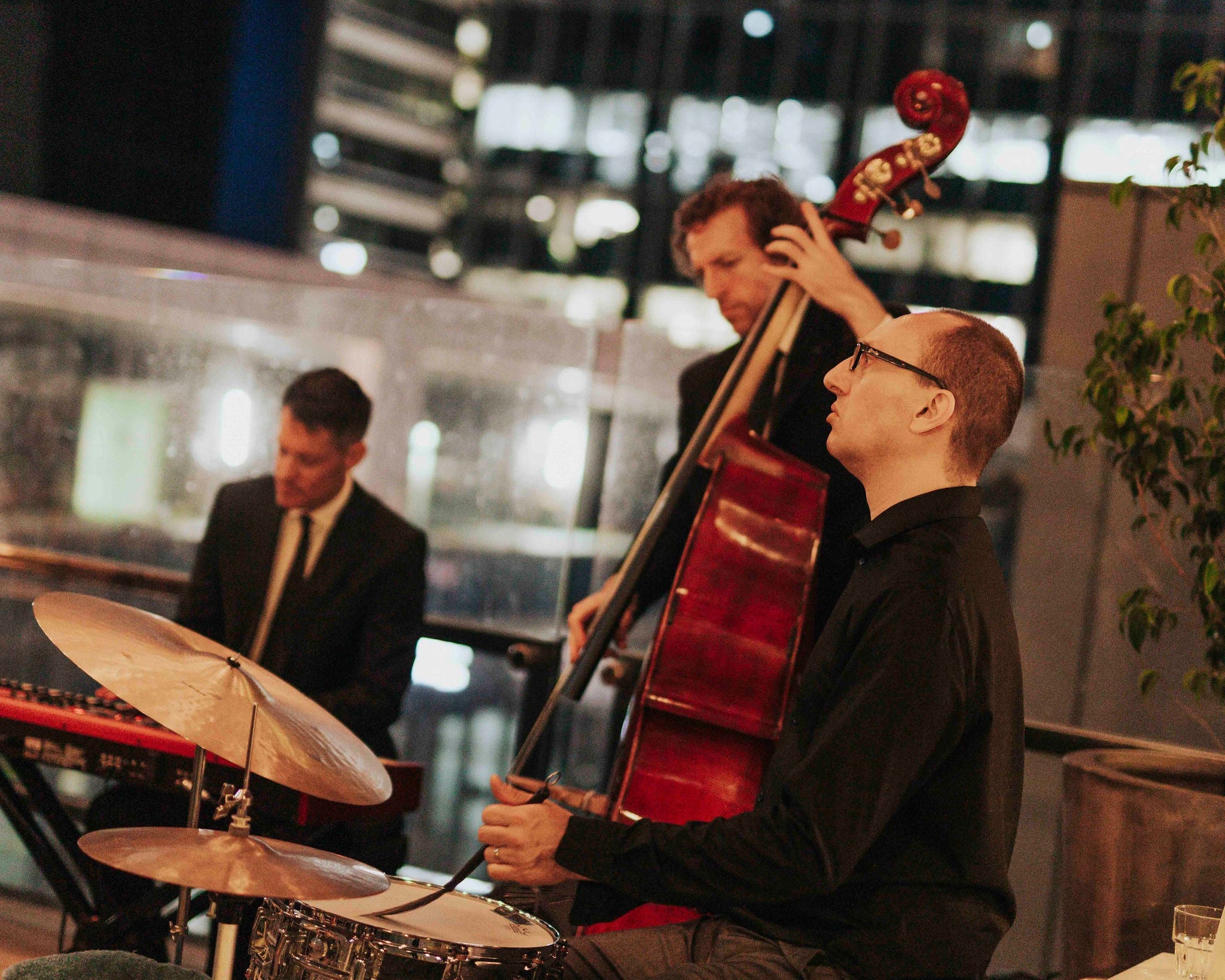 Three musicians performing on a rooftop with cityscape in the background